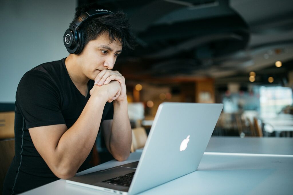 Mann mit Kopfhörern verfolgt einen Online-Kurs zur Fortbildung am Laptop