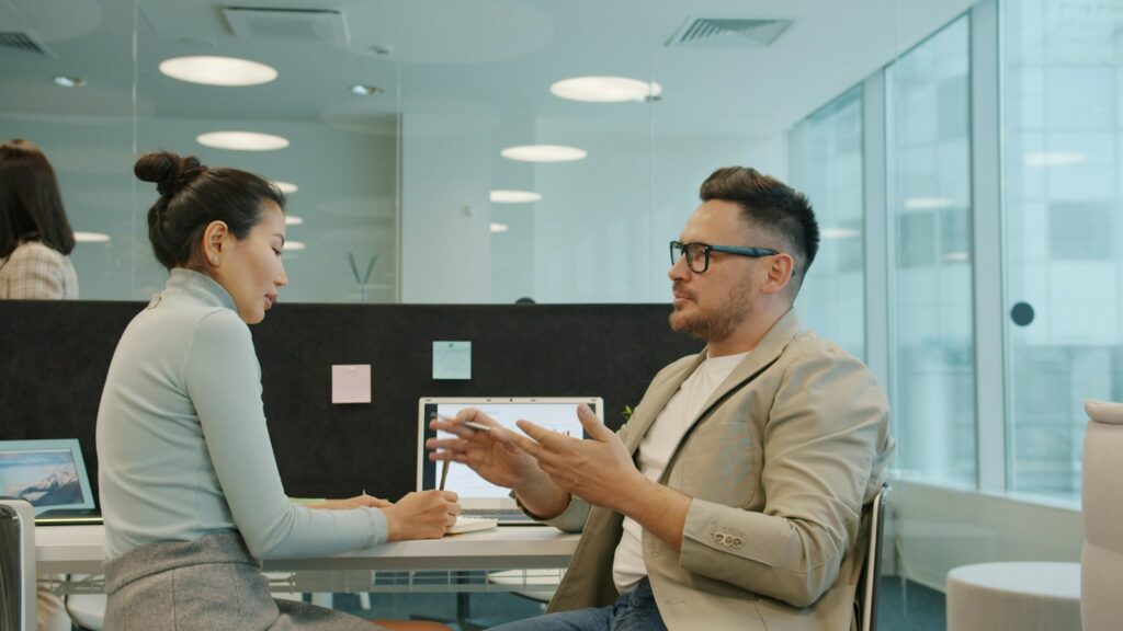 Zwei Kollegen sprechen im modernen Büro über eine Führungsposition und das Auswahlverfahren