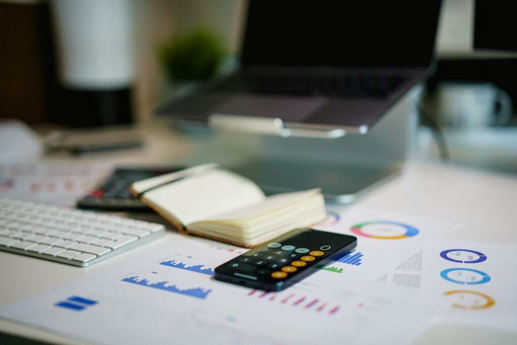 E-Rechnung digital verarbeiten: Schreibtisch mit Smartphone und ausgedruckten Finanzdiagrammen