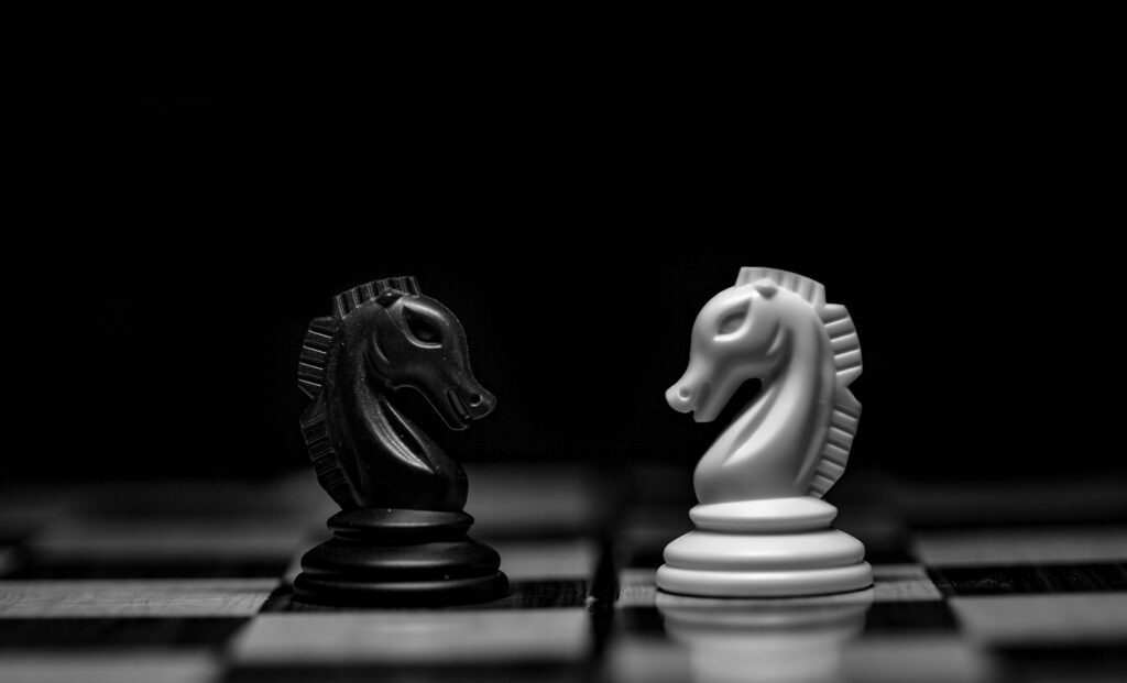 Strategische Entscheidung: Schwarzer und weißer Springer stehen sich auf dem Schachbrett gegenüber