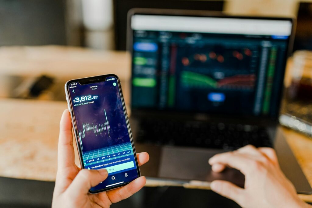 Person vergleicht Kosten eines Indexfonds-Sparplans auf Smartphone und Laptop