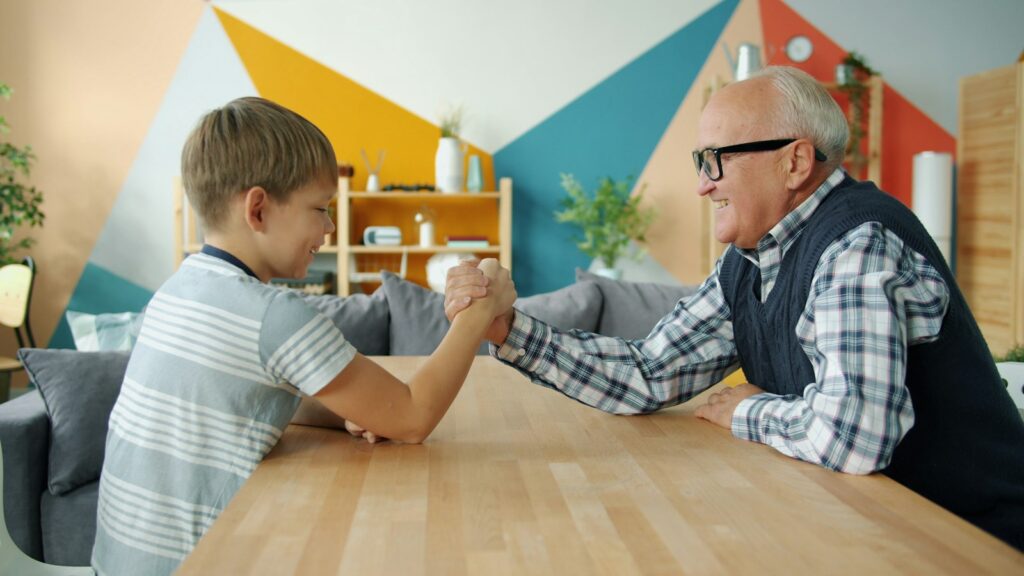 Großvater und Enkel sitzen am Tisch, Symbol für eine Familienverfassung über Generationen