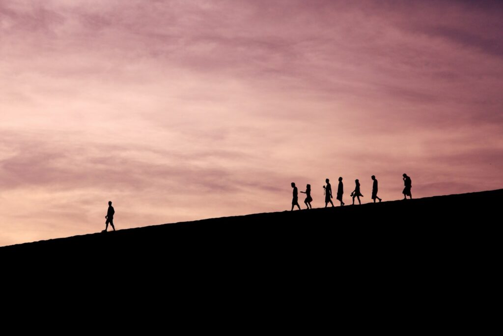 Krisenführung als Orientierung: Silhouetten von Menschen auf einem Hügel vor weitem Horizont