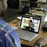 Remote Leadership: Führungskraft leitet eine Videokonferenz mit ihrem verteilten Team am Laptop