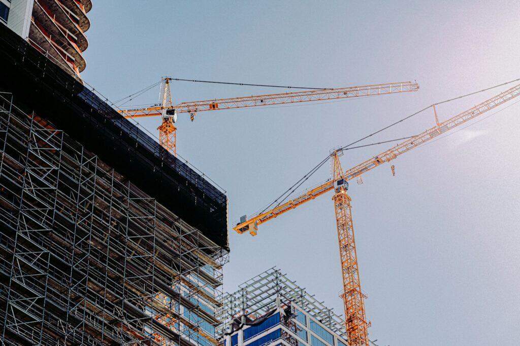 Gelber Baukran an einem Neubau als Symbol für Baukosten und Bauüberhang