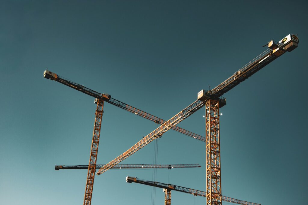 Wohnungsbau: Baukräne vor blauem Himmel über einer Neubaustelle